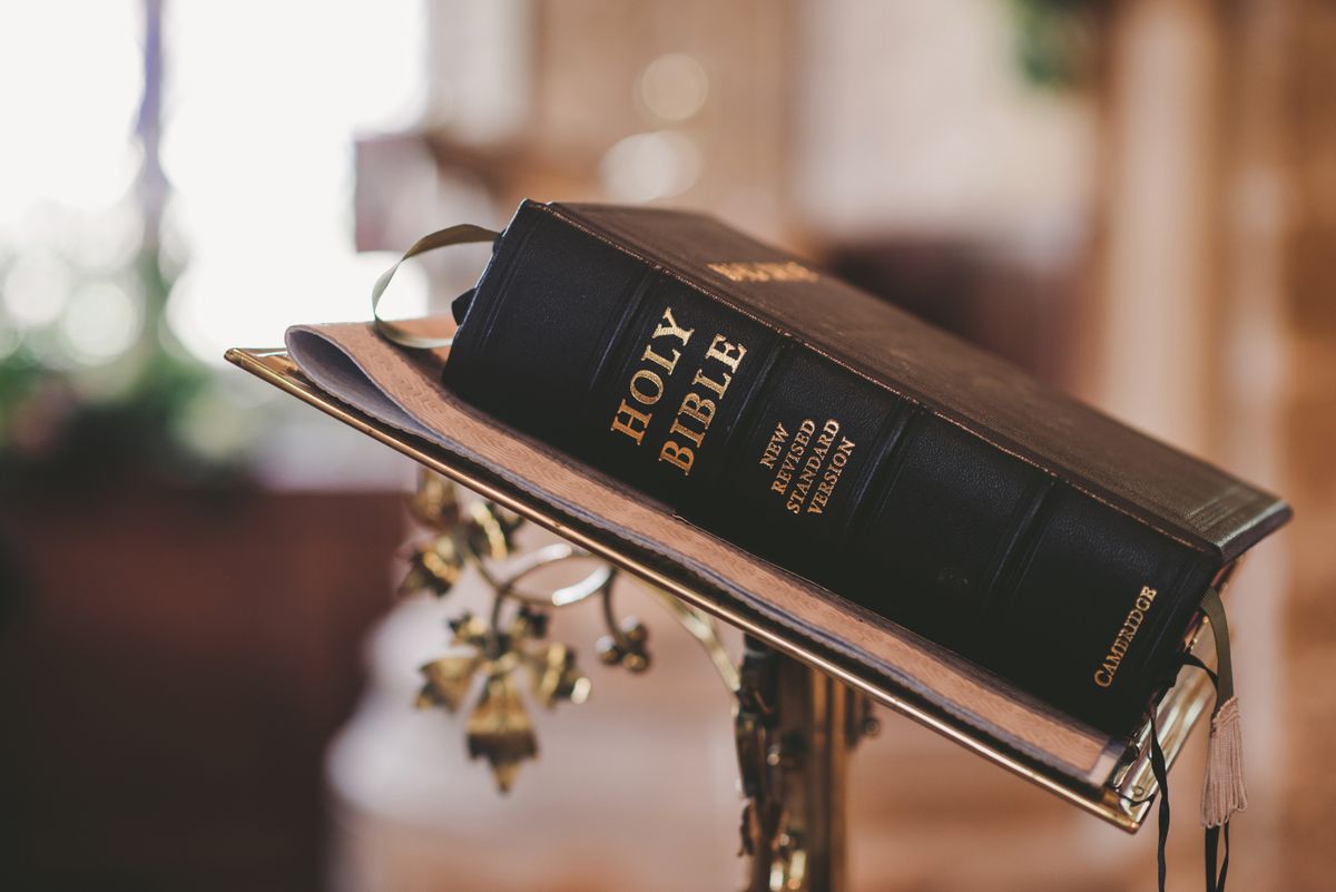 An open Bible resting on the pulpit in warm light