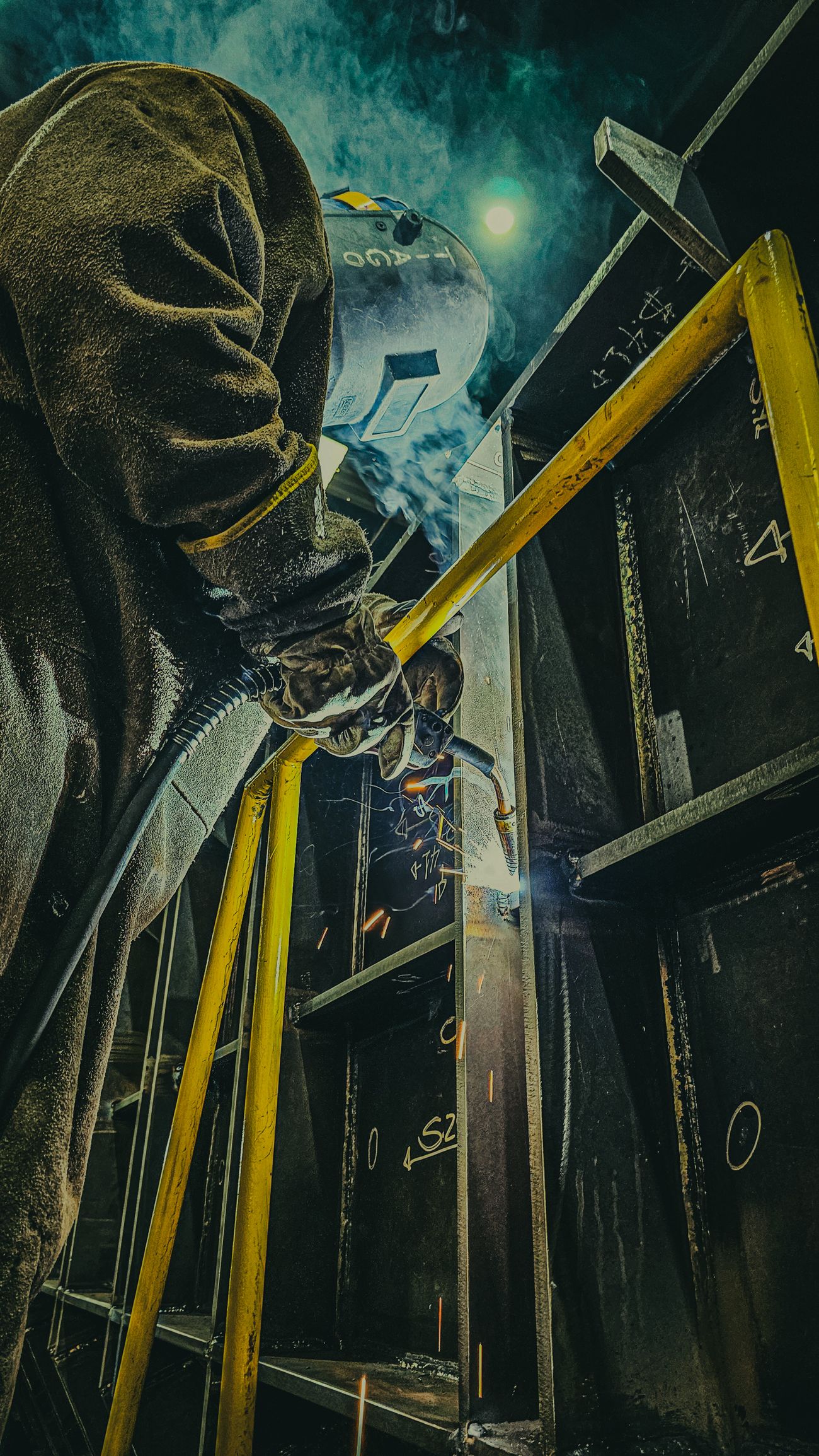 A welder fabricating steel with sparks in the shop