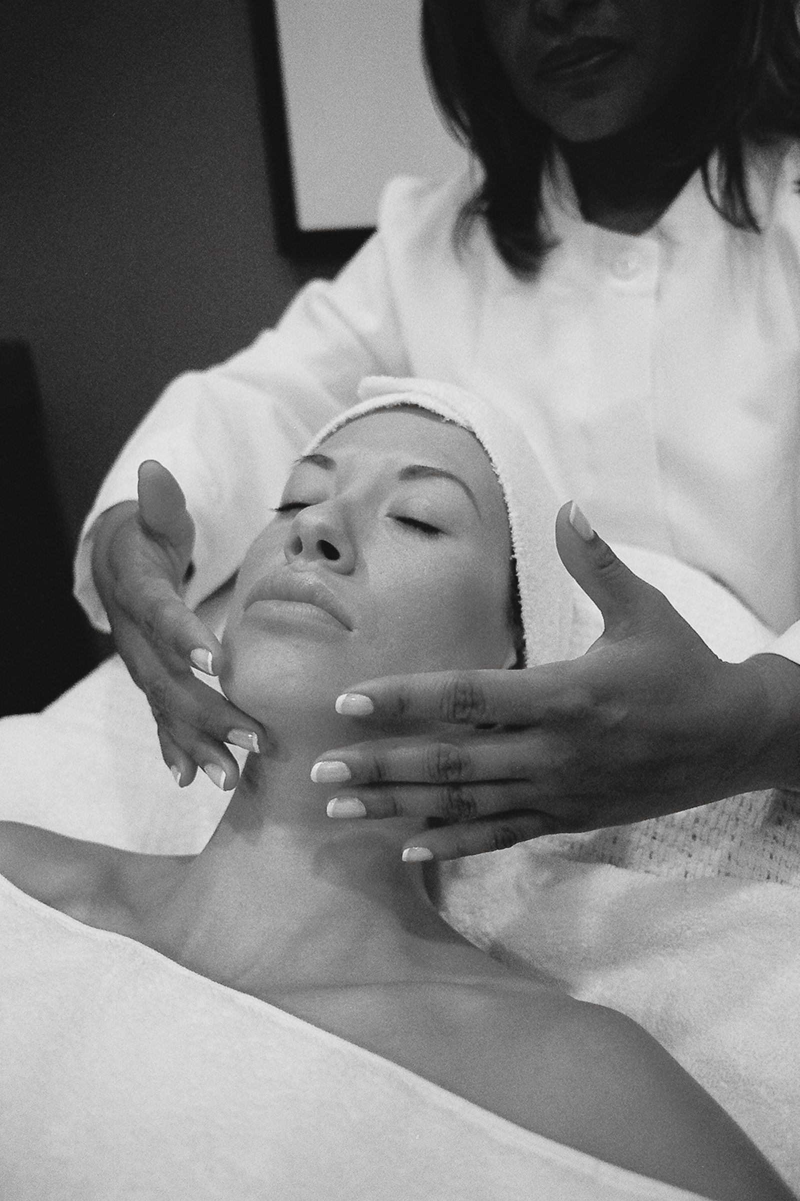 An esthetician performing a slow facial massage on a relaxed guest