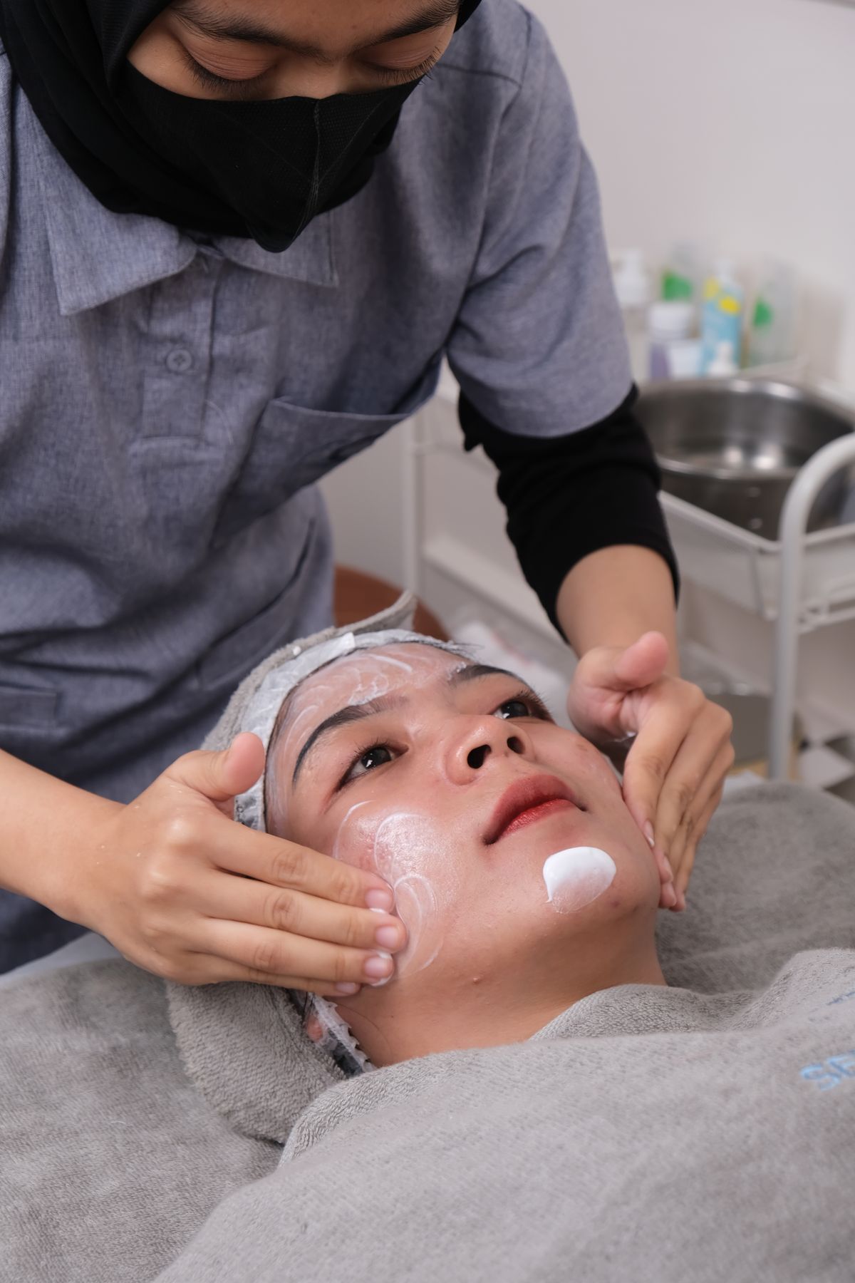 An esthetician applying a treatment mask during a facial